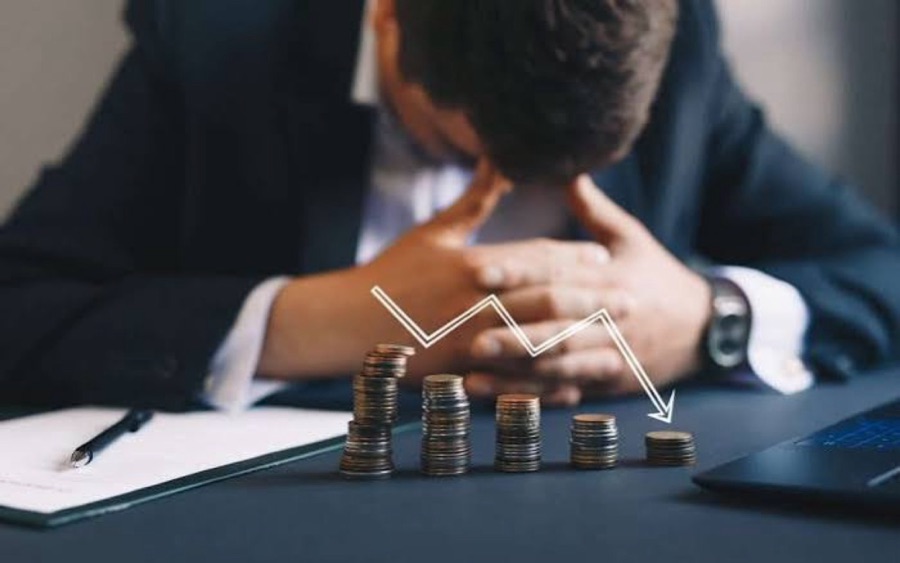 A man with his head in his hands over falling coins