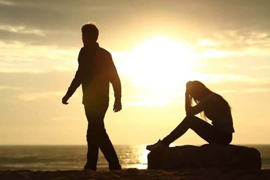 Two people apart in silhouette at sunset